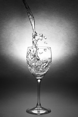 Water poured with a splash into a glass goblet