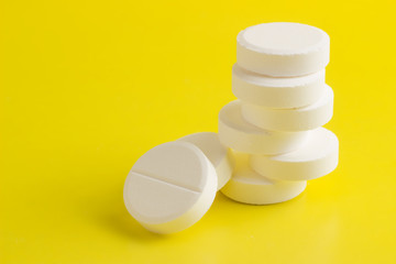 Round pills stacked on a yellow background © Sklyarov