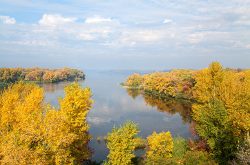 Naklejka premium Yellow trees and blu sky are reflected in the still waters of the river Dnipro