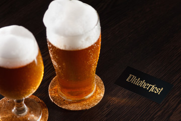 Beer glass pint on a wooden background with foam and Oktoberfest text.