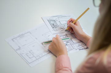 Mão de mulher trabalhando,  desenhando em mesa branca uma planta baixa arquitetônica, engenheira, construção.