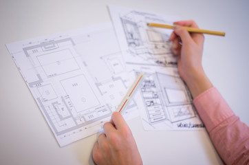 Mão de mulher trabalhando,  desenhando em mesa branca uma planta baixa arquitetônica, engenheira, construção. - obrazy, fototapety, plakaty
