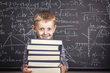 Caucasian child with plaid shirt and braces in front of a classic slate school blackboard. happy and positive expression.