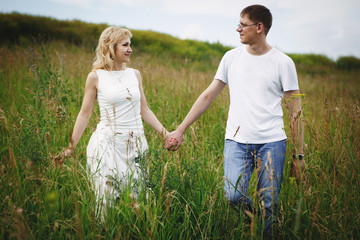 Romantic Couple Running In Field Holding Hands