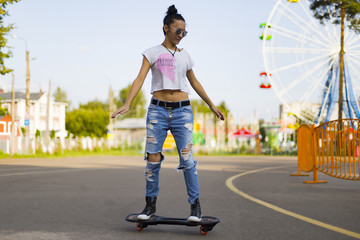 Obraz premium Summer , the girl in the Park riding a skateboard