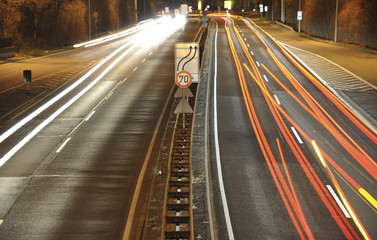 Fototapeta na wymiar Car lights on german highway construction site with signs at night, long exposure photo of traffic