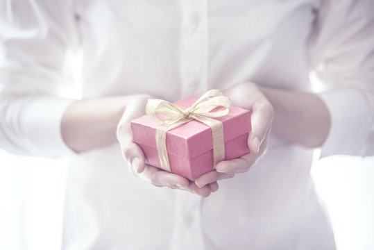 Closeup, Woman hand holding red gift box with copy space background, female giving gift, New year holidays and greeting season concept.