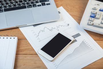 Open laptop with digital tablet and white smartphone, business and investment concept