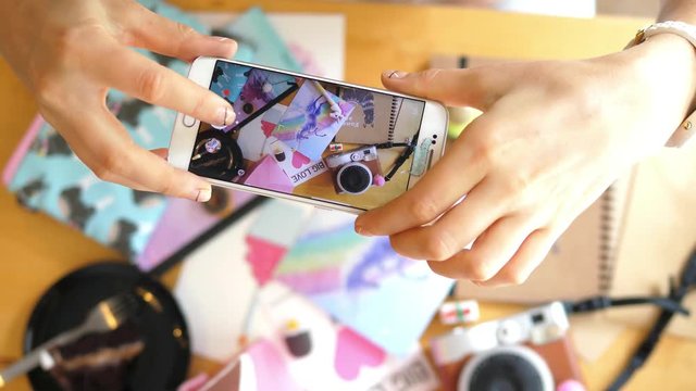 Hands Taking Photos Of Creative Flat Lay of Workspace Desk With Smartphone. Closeup. 4K. 