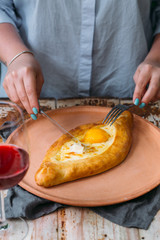 woman having traditional georgian lunch or dinner of khachapuri and wine served on wooden table