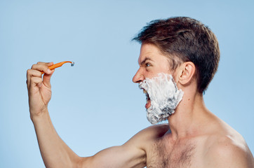 man in shaving foam holds a razor, scream, emotions, portrait