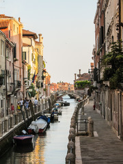 Venice, Italy - Circa July 2015: Tourists and boats at sunset in the canals of Venice