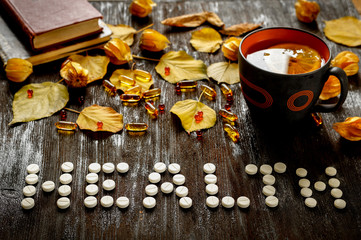 Concept of cold autumn - pills, leaves on dark wood