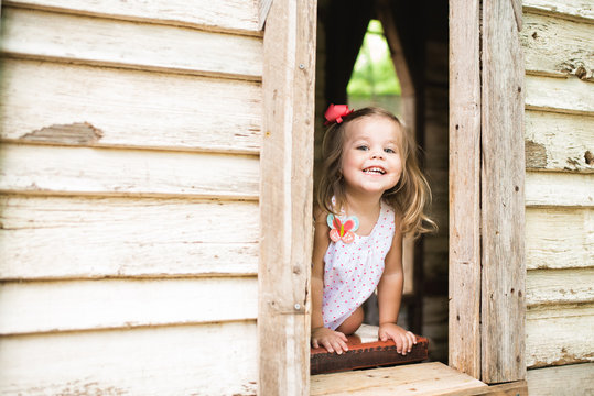 Girl peeks out window of wooden house