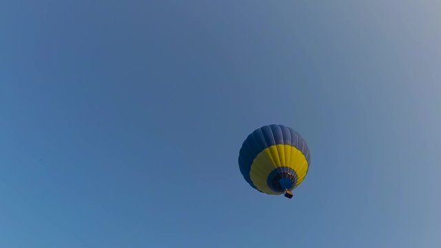 Big balloon of yellow and blue color in a blue sky view from the earth
