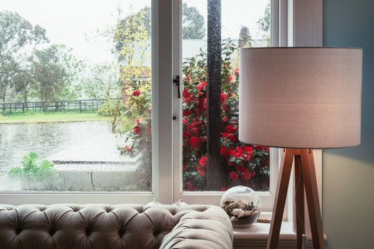 Fototapeta view through a rainy window from inside with sofa and lamp