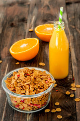 flakes in bowl with orange juice on dark wooden background