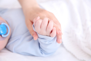 Obraz na płótnie Canvas Mother holding hand of cute baby, closeup