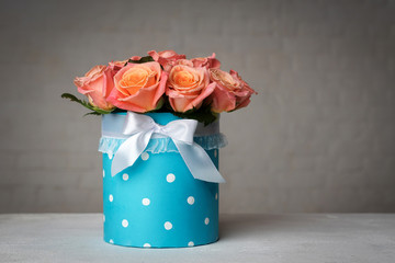 pink-orange roses in a turquoise box tied with a bow