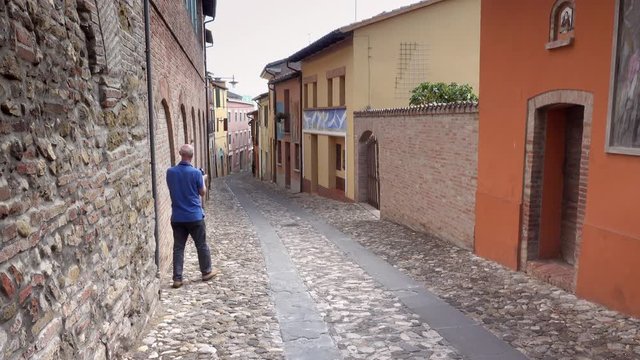 man taking photo of street of the medieval village of Dozza, a small gem among the architectural wonders of Italy