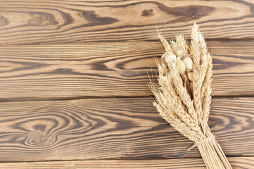 One bundle of wheat and poppy tied up of brown rope on old rustic wooden planks