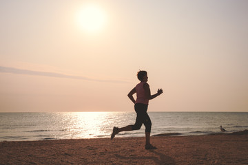 Fototapeta na wymiar senior woman jogging on sea beach at the sunrise