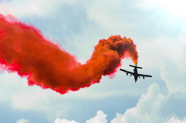 Airplane fly in zigzags with a red trail smoke in the sky