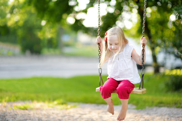 Cute little girl having fun on a playground outdoors in summer.