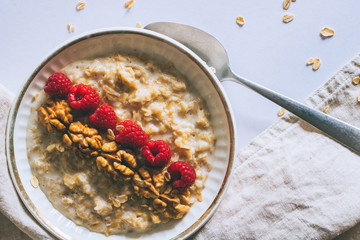 Morning breakfast, oatmeal in milk with raspberries on a white background, top view