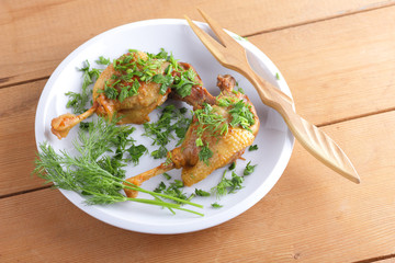 Fried duck leg on a white plate sprinkled with herbs for a restaurant