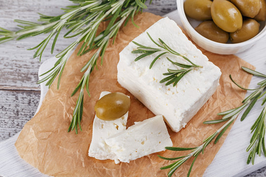 Fresh feta cheese with rosemary on white wooden serving board