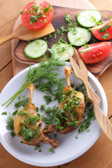 Roasted duck legs with cucumbers, tomatoes and herbs on a white plate