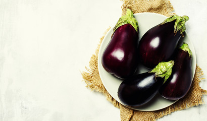 Fresh eggplants on plate, top view