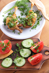 Roasted duck legs with cucumbers, tomatoes and herbs on a white plate