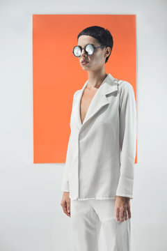 Fashion/conceptual portrait of female model on white adn orange background.