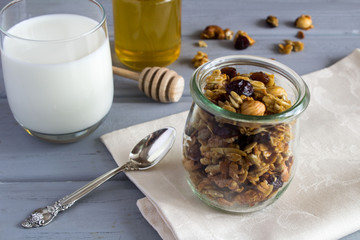Healthy  breakfast: granola, milk and honey on the  grey wooden background 