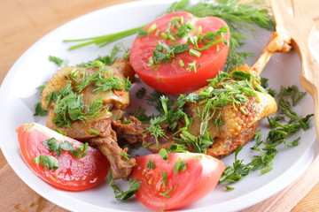 Roasted duck legs with tomato and herbs with wooden cutlery