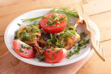 Roasted duck legs with tomato and herbs with wooden cutlery