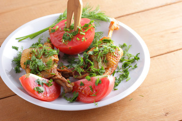 Roasted duck legs with tomato and herbs with wooden cutlery