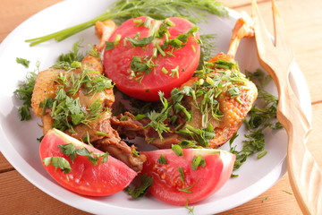 Roasted duck legs with tomato and herbs with wooden cutlery