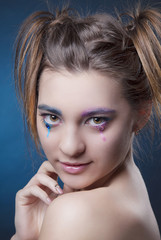 Fototapeta premium Close-up portrait of girl with bright makeup and clean skin on blue background
