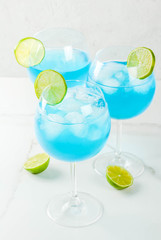 Alcohol drink. Glasses with a blue alcoholic cocktail with ice and lime garnish. Blue Curacao. Liquor. Copy space