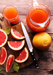 Grapefruit juice and ripe grapefruits on a wooden background