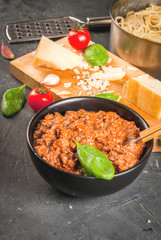 Ingredients of Italian cuisine. Products for the preparation of pasta bolognese, the cooking process. Welded spaghetti in pan, bolognese sauce, basil, garlic, tomato, parmesan Copy space