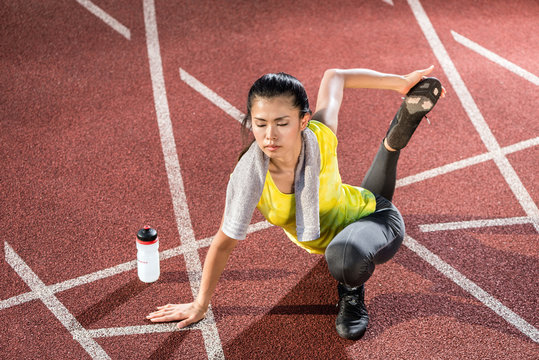 Woman sprinter doing warm up exercise before sprint outdoors