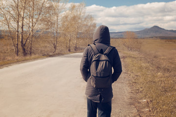 a lone man with a backpack walking along the road