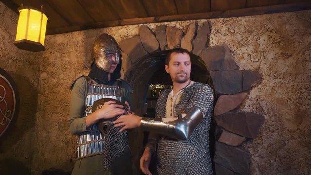 Two caucasian men dressed as medieval warriors entering room with stone walls, taking off helmet and looking around. Shot with Sony a7s and Atomos Ninja Flame