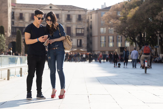 Young couple in Barcelona looking at their mobile phone