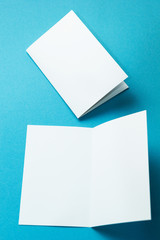 A blank invitation greeting card, a brochure isolated on a turquoise, to replace your design. Vertically.