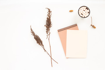Autumn workplace. Notebook, pine cone, dried branches, cup of coffee, marshmallow on white background. Flat lay, top view. Autumn background